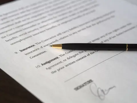 A typed agreement with an Insurance clause and a signature line, with a black and gold pen lying across the page