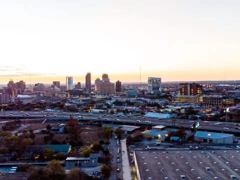 Downtown San Antonio at dusk seen from above, with an elevated freeway carrying traffic across the city in front of the skyline